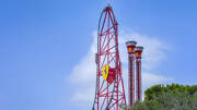 Les rails rouges vertigineux de l'attraction Red Force à Ferrari Land, au parc PortAventura World, avec le logo Ferrari visible, sous un ciel bleu parsemé de nuages blancs.